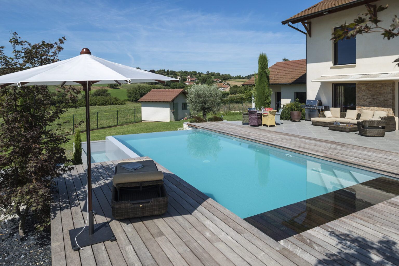 Piscine à débordement avec plage en bois