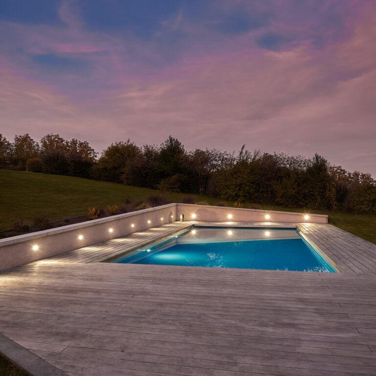 Piscine extérieure de 11 x 4.5 m avec spot leds et plage en bois exotique