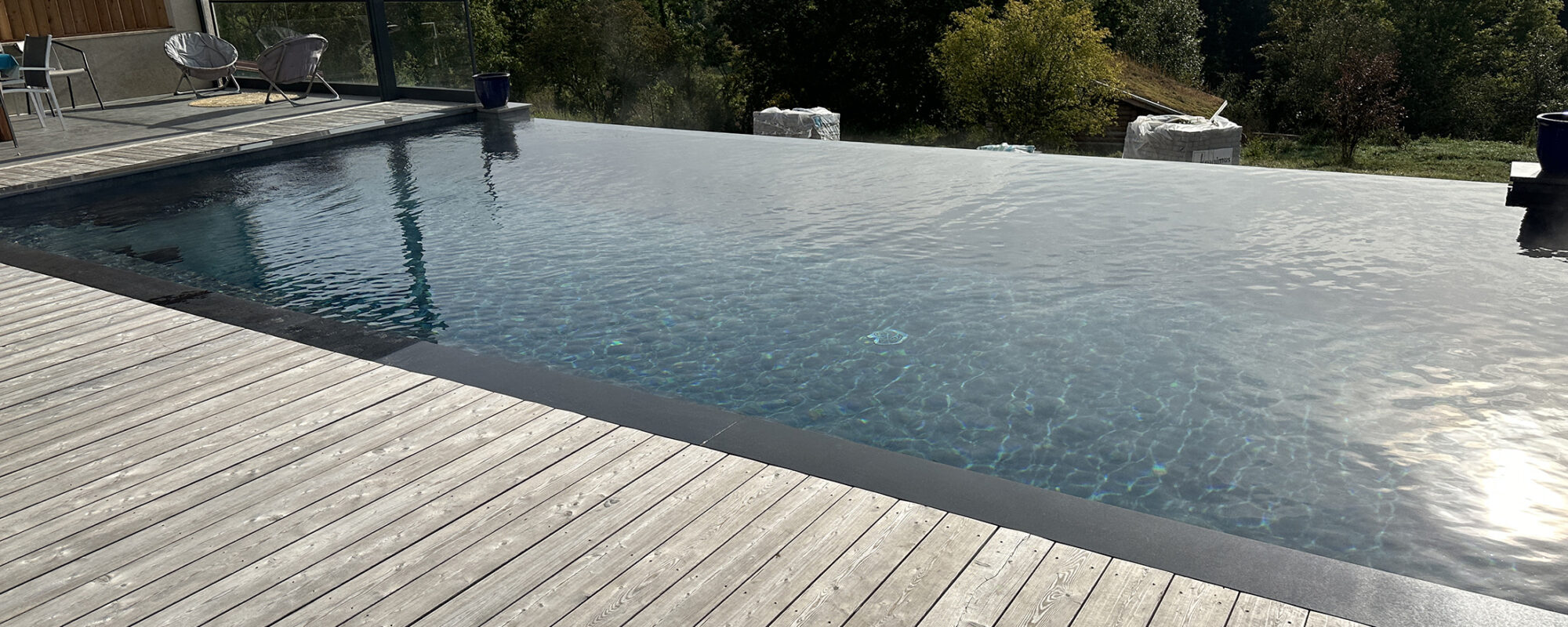 Piscine à débordement avec plage en bois