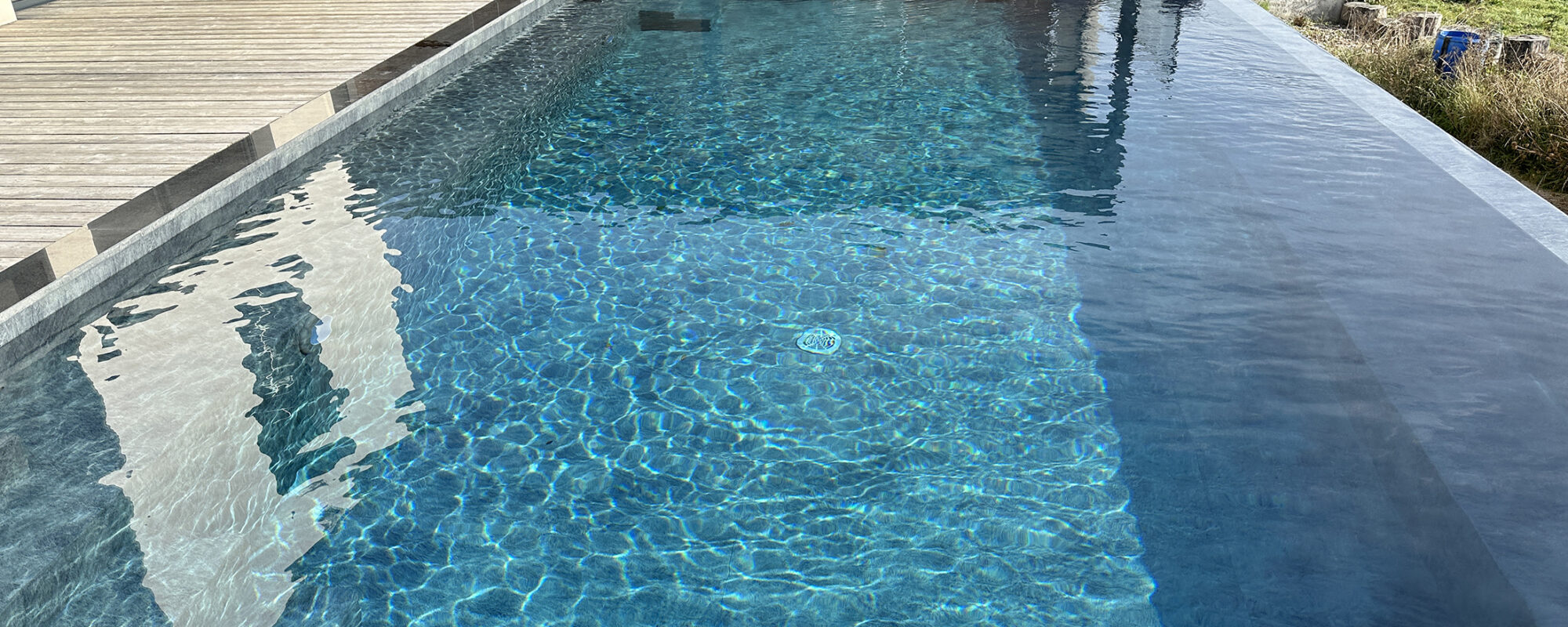 Piscine extérieure à débordement avec plage en bois