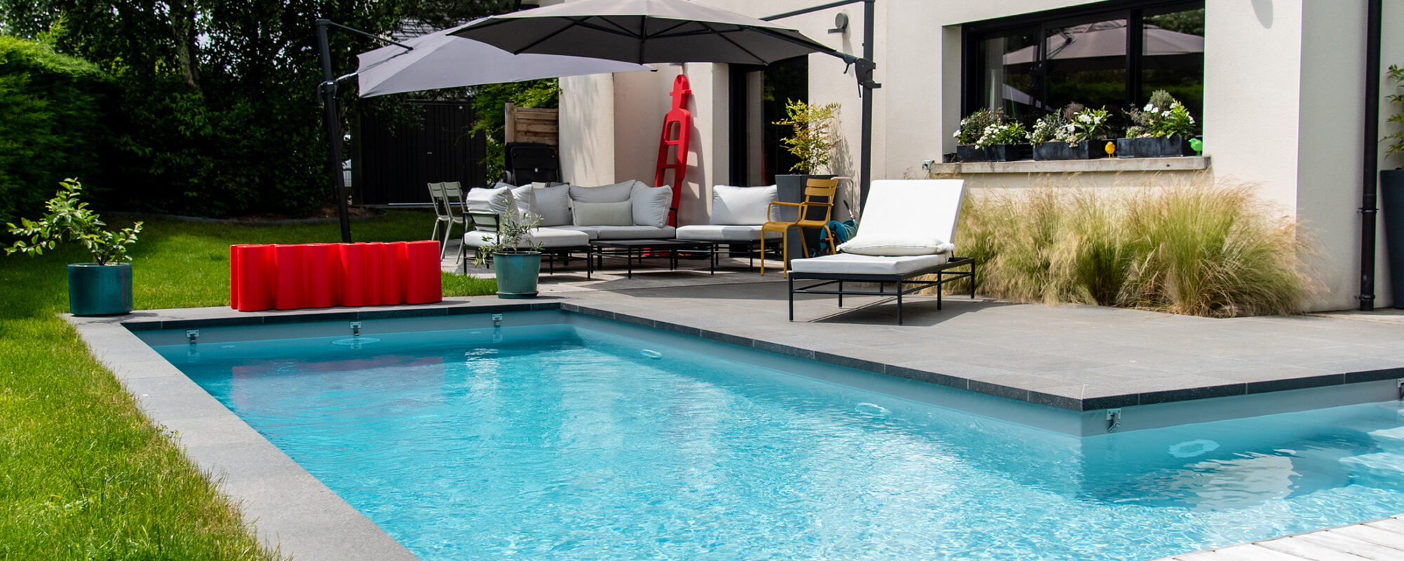 Piscine en L avec liner gris clair et margelles en Basalt