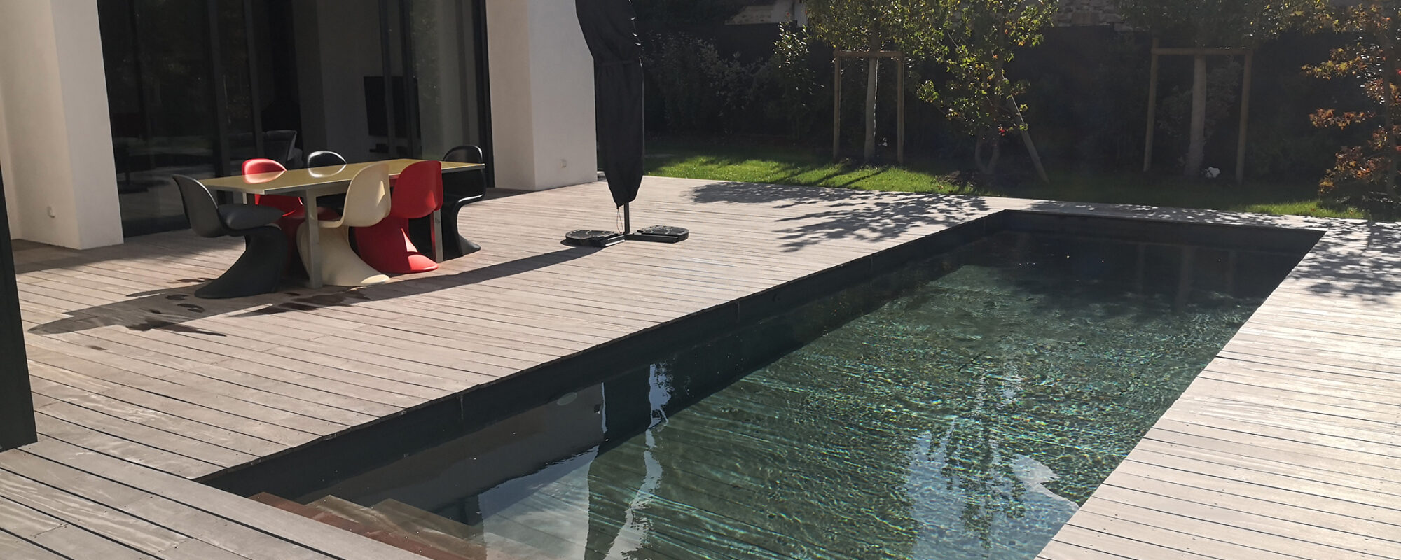 Piscine extérieure avec plage en bois et fond mobile