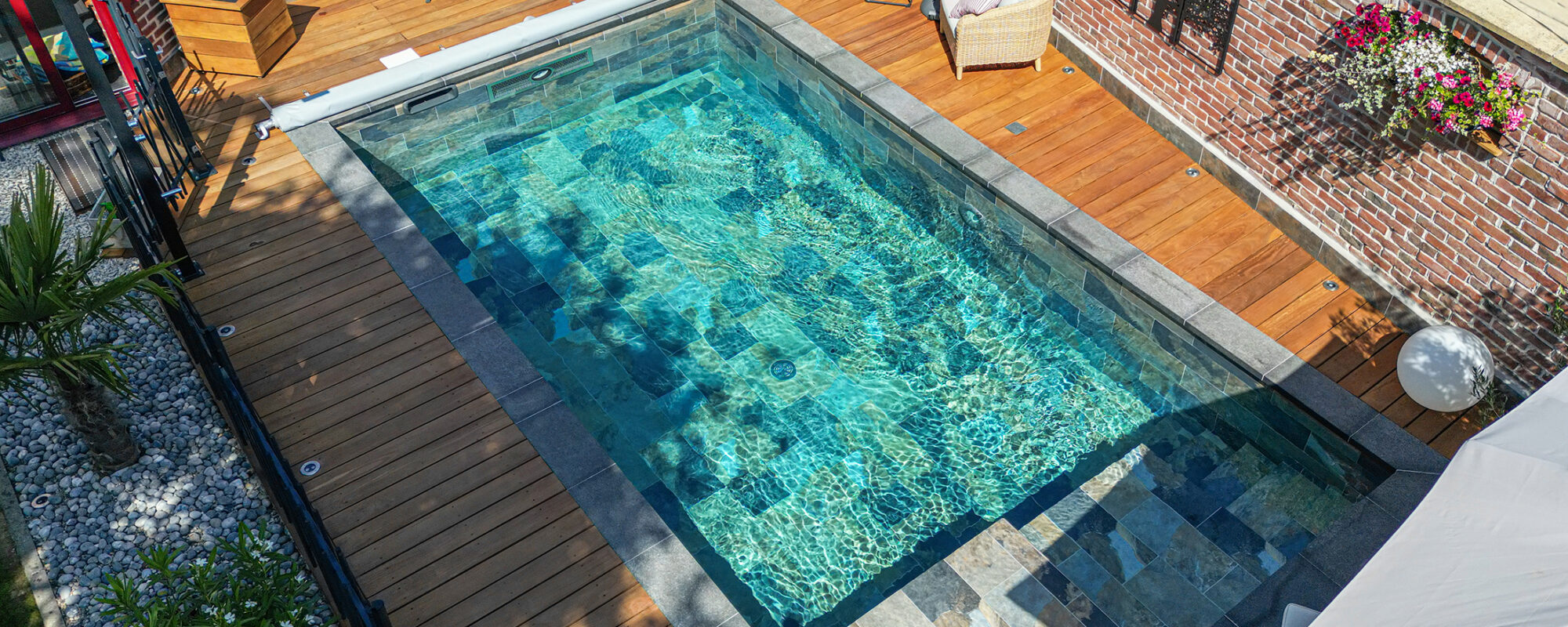 Piscine avec margelles en basalte et plage en bois