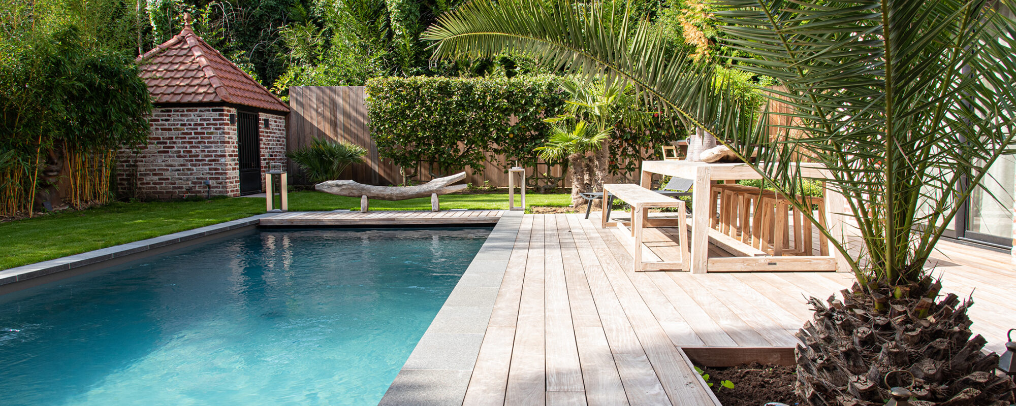 Piscine avec margelles en pierre naturelle et plage en bois