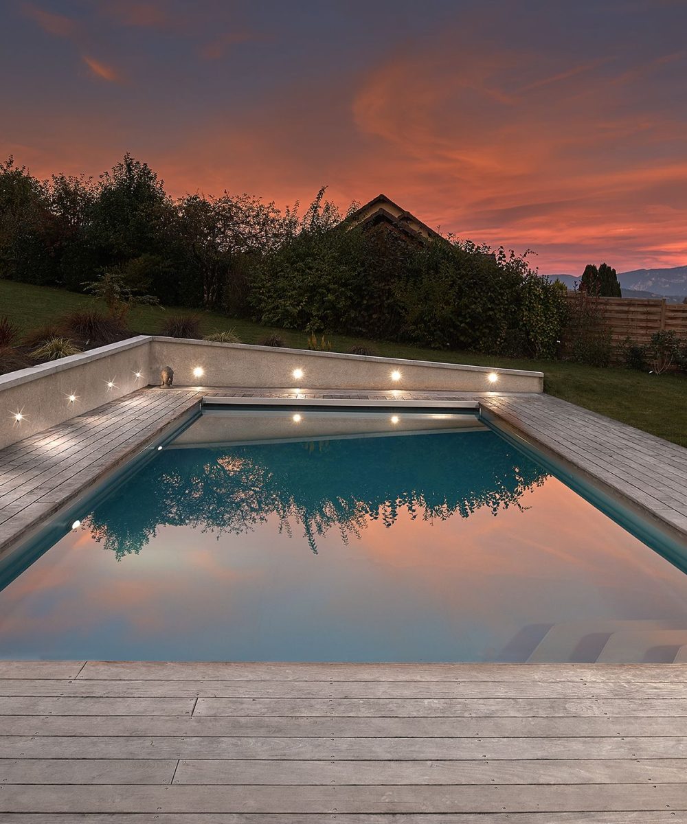 Piscine extérieure de 11 x 4.5 m avec spot leds et plage en bois exotique